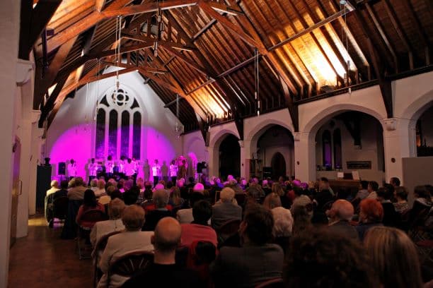 Llun:  cynulleidfa yn neuadd yr eglwys  Credyd  Betina Skovbro